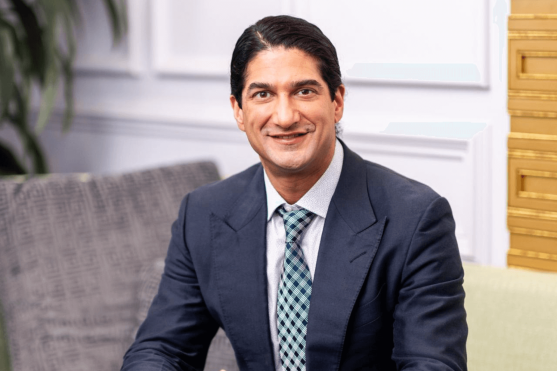 Board-certified facial plastic surgeon seated in consultation lounge, ready to discuss facelift goals and recovery.