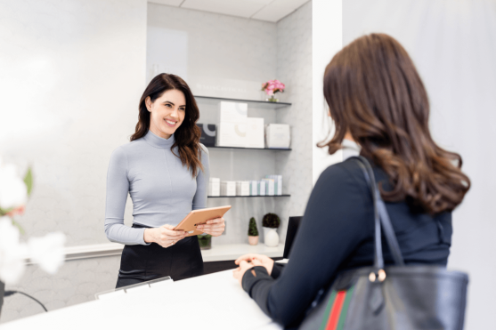 A patient consulting with front-desk staff at The Practice Healthcare about tummy-tuck recovery timelines